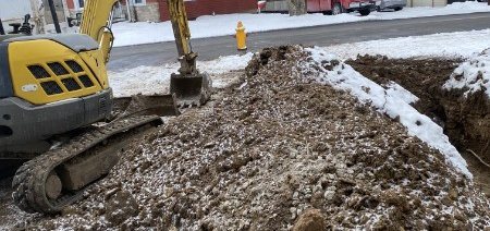Excavator opening a utility trench at the roadside