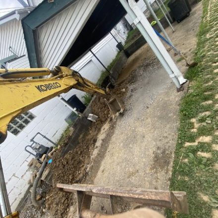 Excavator digging beside a house for a service line replacement