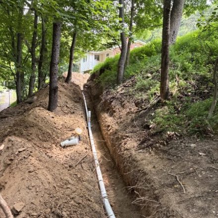 Long open trench with new pipe run through woods